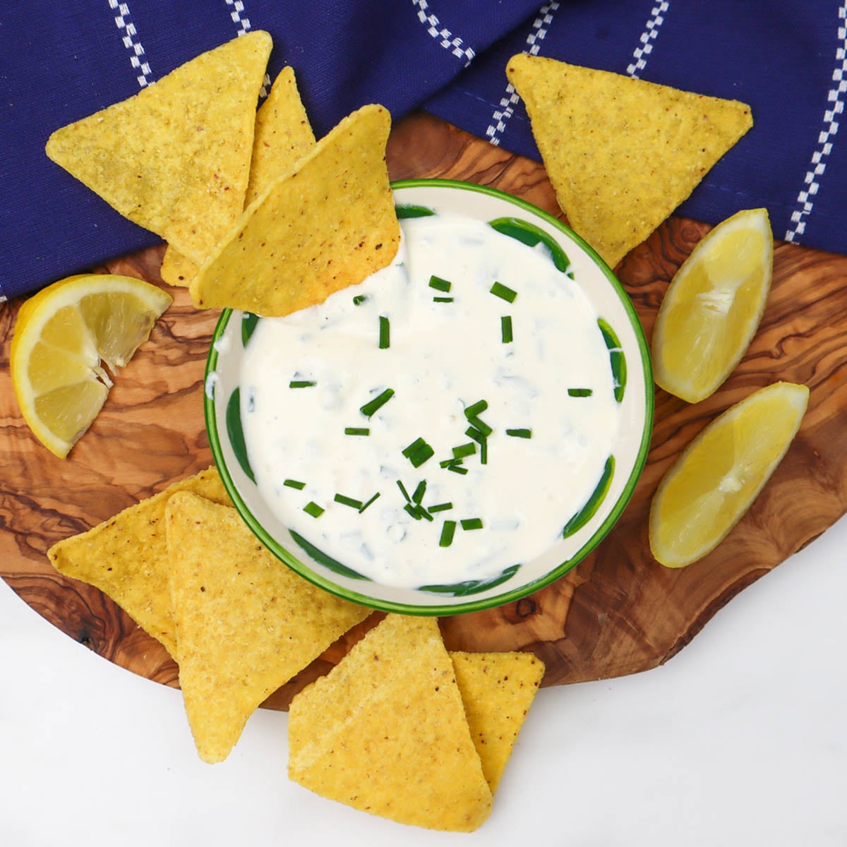 Sour Cream and Chive Dip A bowl of sour cream and chive dip surrounded by tortilla chips and lemon wedges.