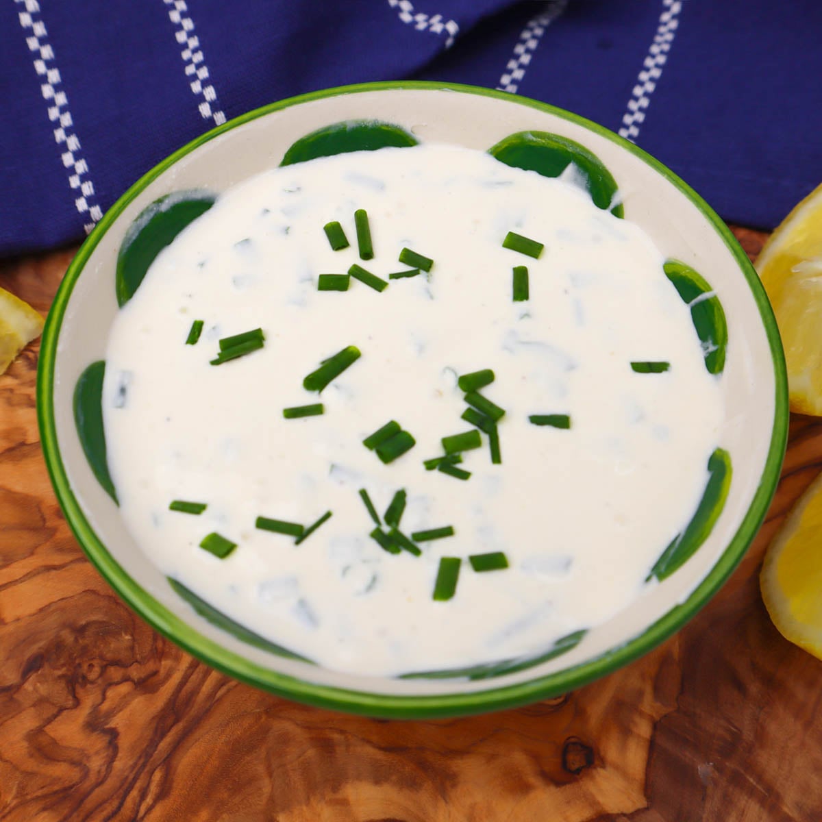 Sour Cream and Chive Dip A bowl of sour cream and chive dip garnished with chopped chives, next to lemon wedges.