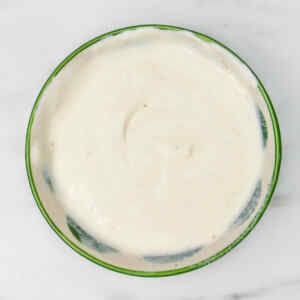 Creamy sour cream and chive dip in a green bowl.