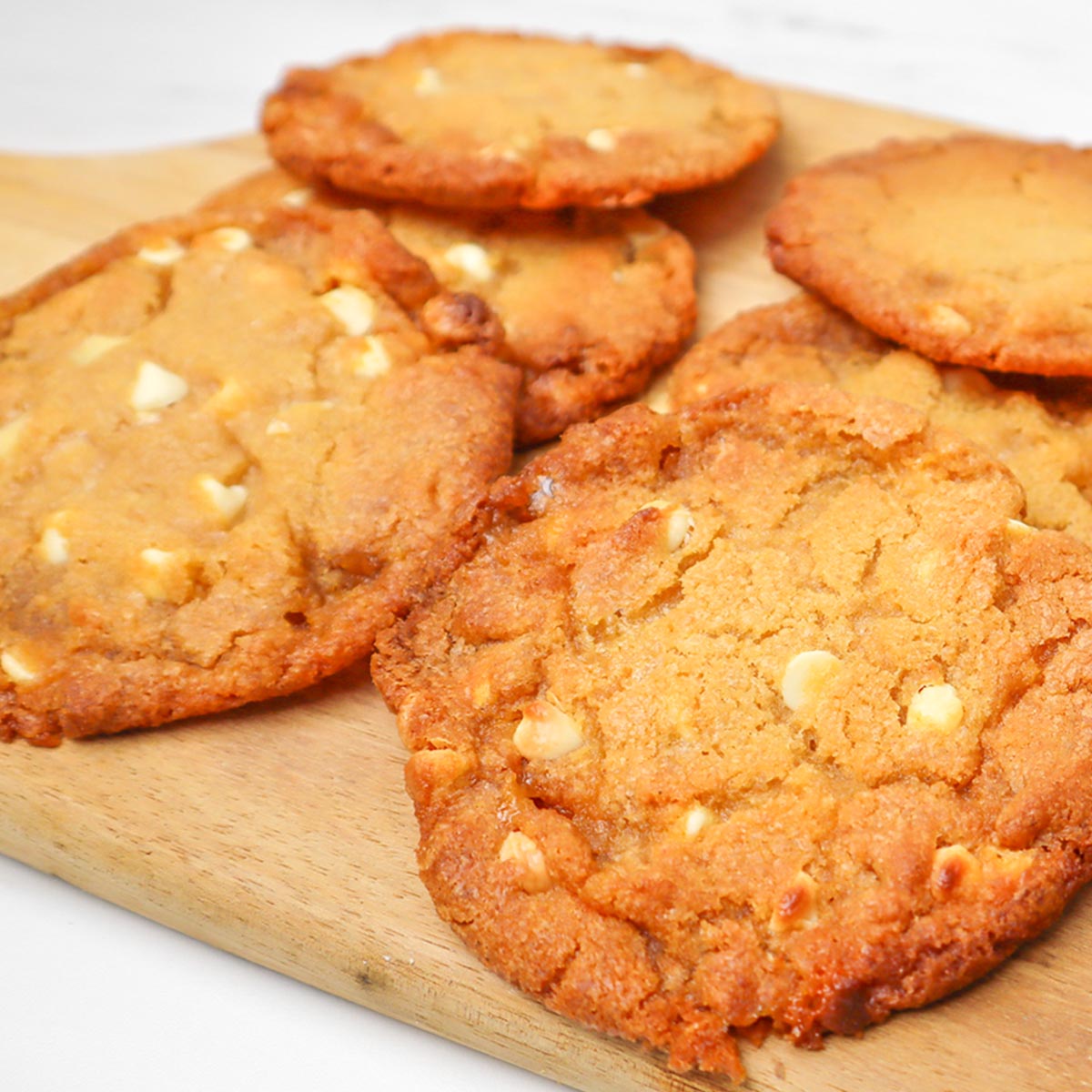 Biscoitos de chocolate branco com gotas de chocolate e favo de mel Biscoitos de chocolate branco com gotas de chocolate e favo de mel, recém-assados, servidos em uma tábua de madeira.
