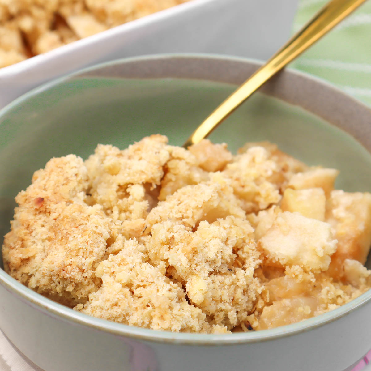 Apple Crumble A bowl of apple crumble topped with a golden, crumbly topping and pieces of baked apples.