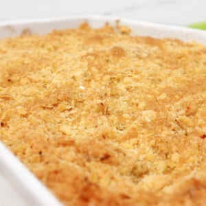 Golden brown apple crumble in a white dish, with a crispy topping.