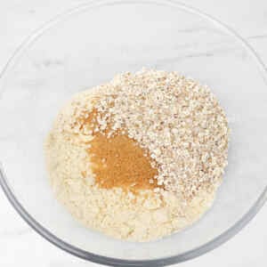 A bowl containing a mixture of flour, oats, and brown sugar for apple crumble.