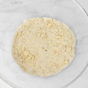 A bowl filled with crumbly mixture for apple crumble.