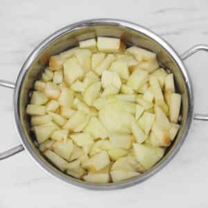 Chopped apples in a stainless steel pot, ready for apple crumble preparation.