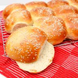 Freshly baked sesame burger buns on a cooling rack.