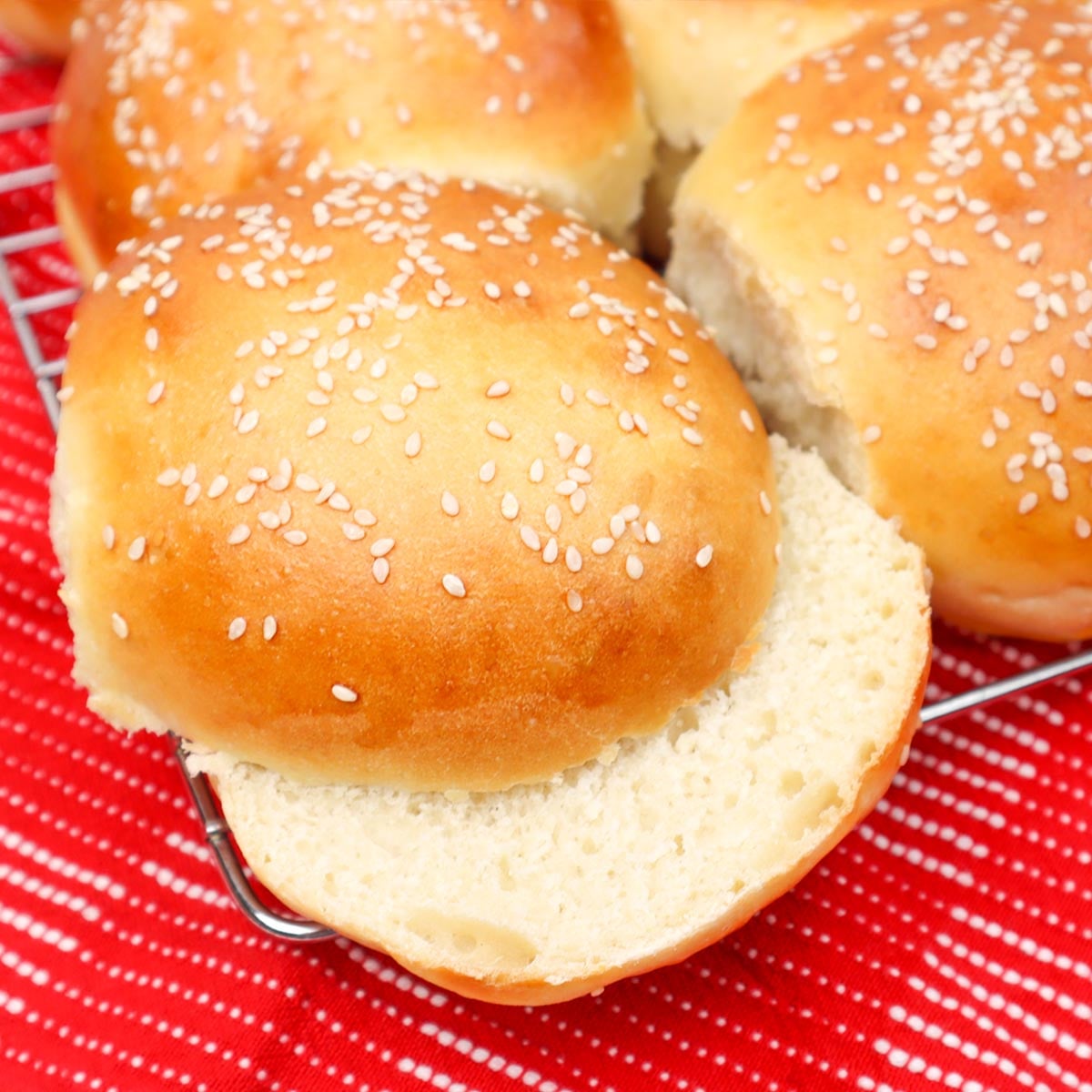 Burger Buns Freshly baked burger buns with sesame seeds on top, resting on a cooling rack.