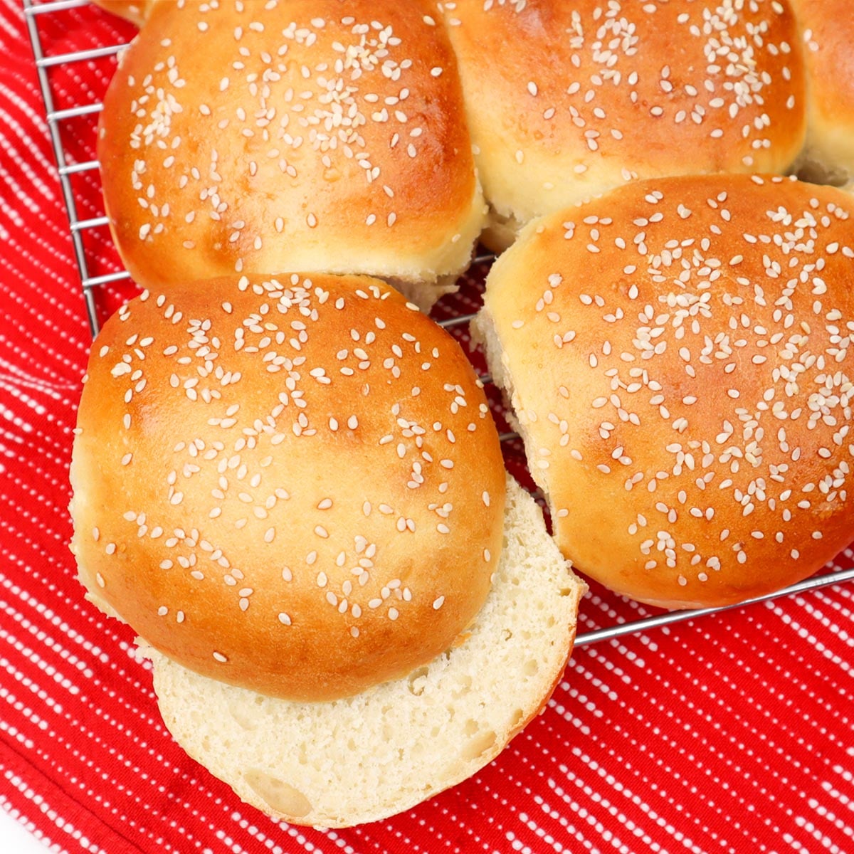 Burger Buns Freshly baked burger buns topped with sesame seeds on a cooling rack.