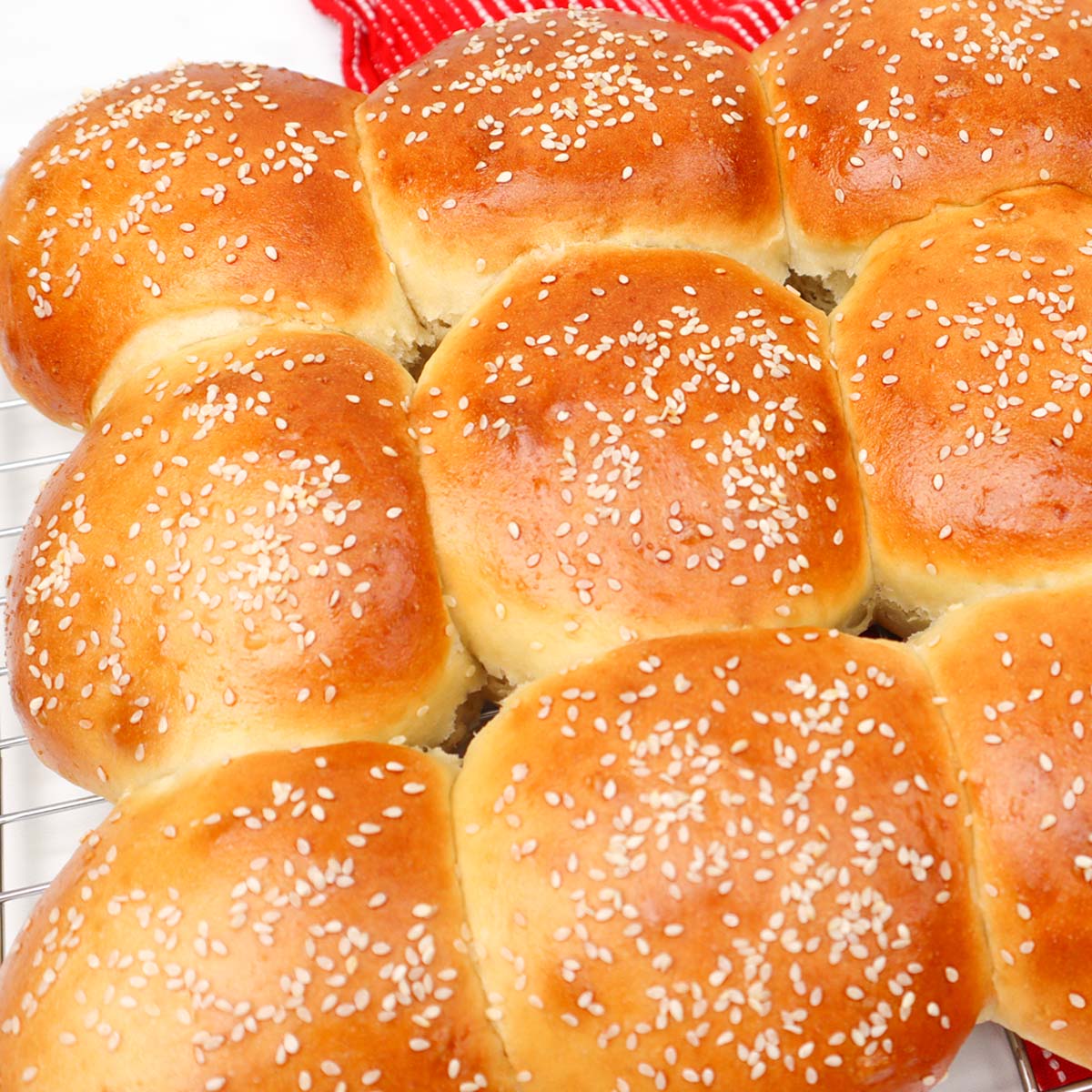 Burger Buns Freshly baked burger buns topped with sesame seeds, arranged on a cooling rack.