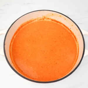 A creamy, cheesy roasted red pepper soup in a pot.