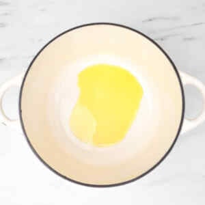 A pot with a small amount of oil at the bottom, ready for cooking.