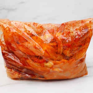 A sealed plastic bag filled with marinated chicken and vegetables for fajitas.