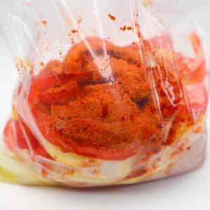 A plastic bag filled with sliced peppers and spices for chicken fajitas meal prep.