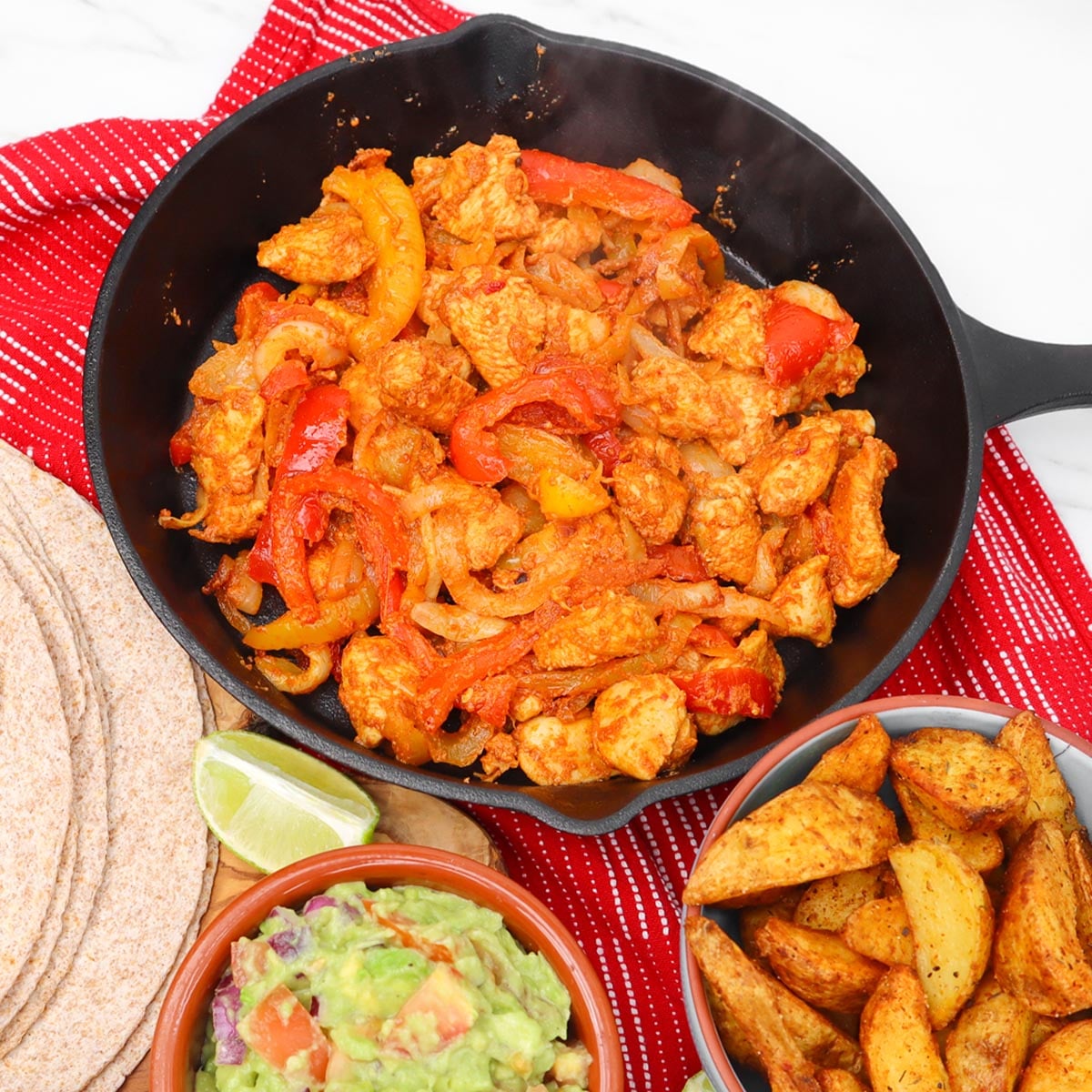 Chicken fajitas Freezer Meal Prep A skillet filled with chicken fajitas, peppers, and onions, served with guacamole and potato wedges.