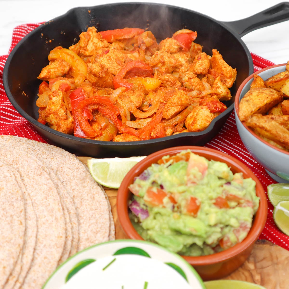 Chicken fajitas Freezer Meal Prep A skillet with sizzling chicken fajitas, surrounded by tortillas, guacamole, and lime wedges.