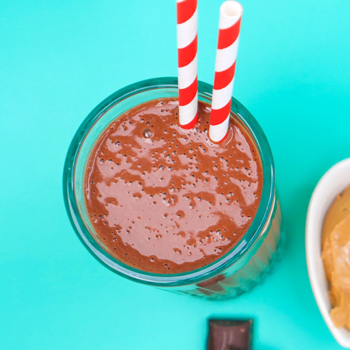 Chocolate Peanut Butter Smoothie Freezer Meal Prep Packs A glass of chocolate peanut butter smoothie with two red and white striped straws.