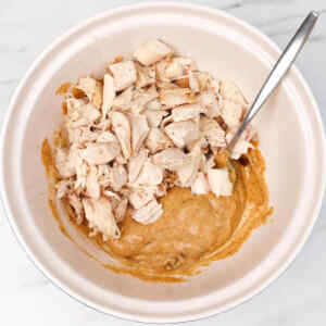 Chopped cooked chicken mixed with a creamy sauce in a bowl.