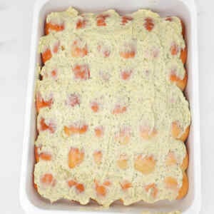 Garlic dough balls topped with a creamy herb mixture in a baking dish.