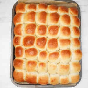 A tray of golden-brown garlic dough balls arranged neatly in rows.