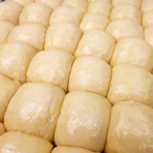 Close-up of soft, shiny garlic dough balls arranged in a grid pattern.