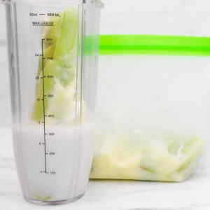 A blender filled with kiwi and avocado, next to a freezer bag for meal prep.