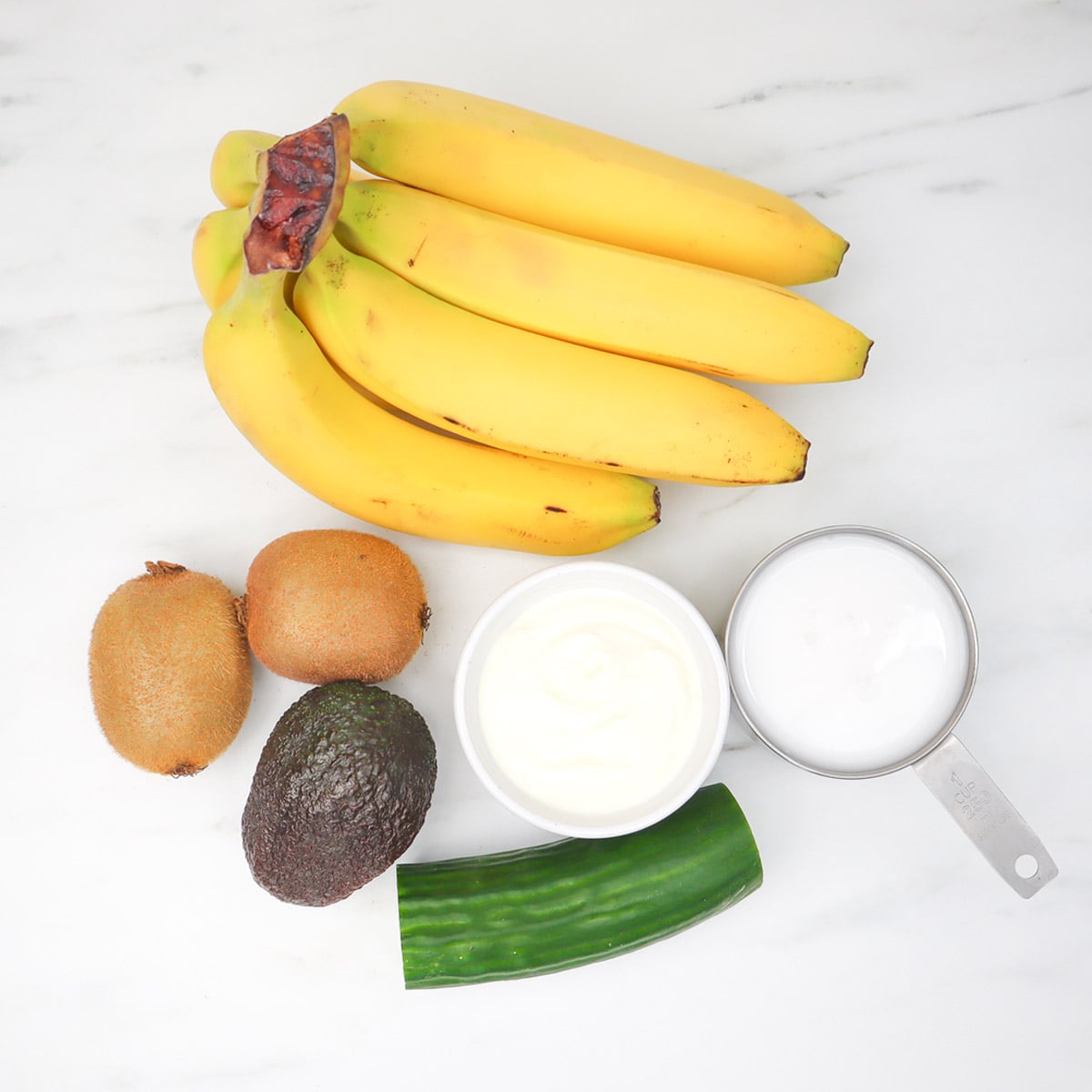 Kiwi and Avocado Smoothie Freezer Meal Prep Packs Ingredients for kiwi and avocado smoothie including bananas, kiwis, avocado, yogurt, and cucumber.