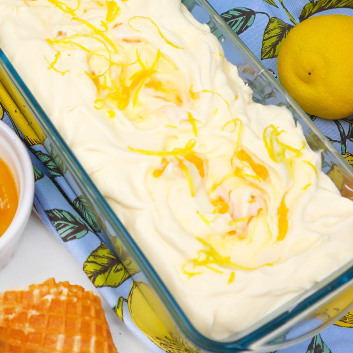 Lemon Ice Cream A creamy lemon ice cream topped with lemon zest, served in a glass dish.