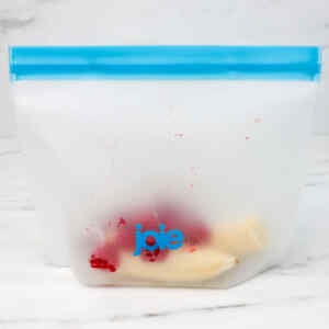 A clear freezer bag containing raspberries and banana slices.