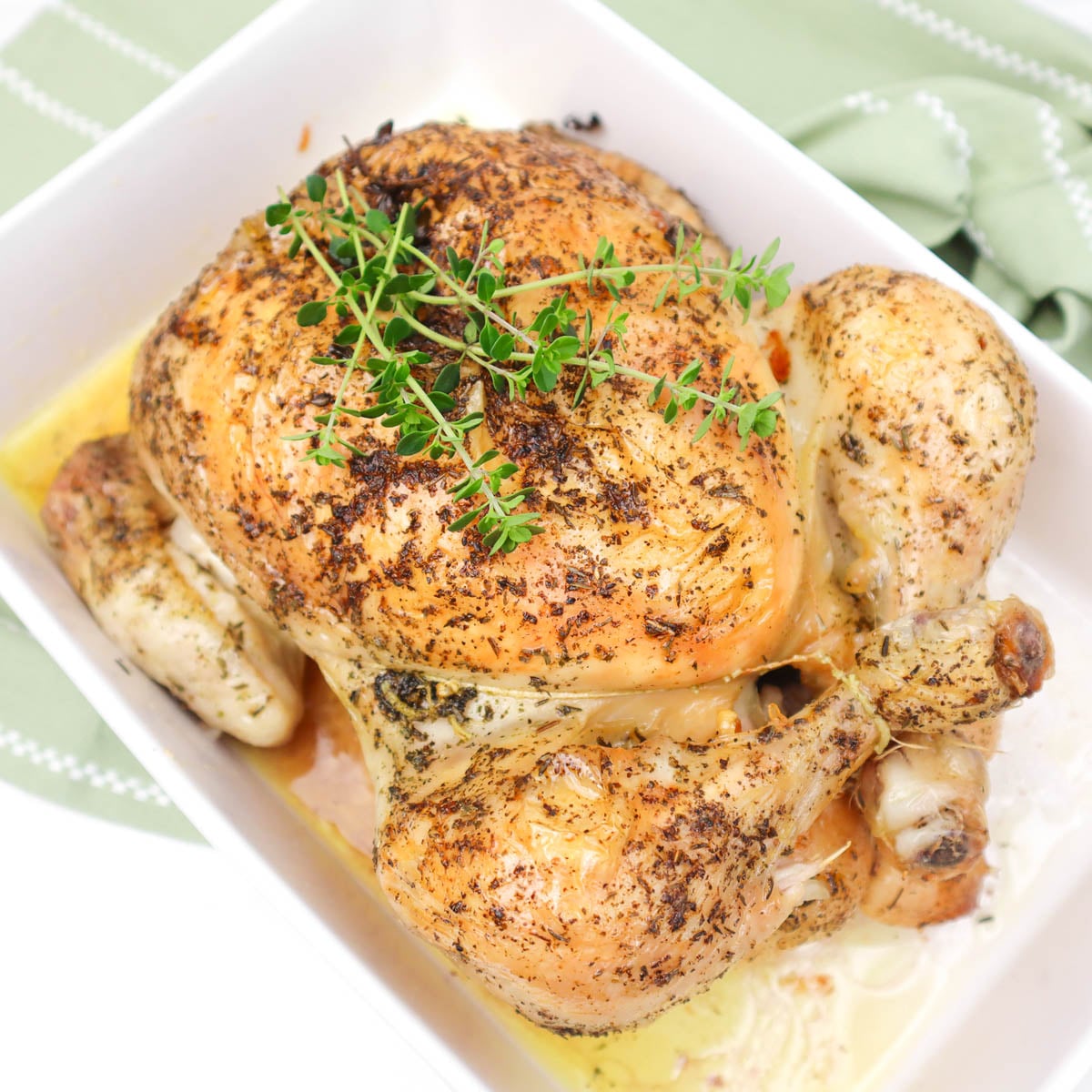 Roast Chicken A perfectly roasted chicken garnished with fresh herbs, served in a white dish.