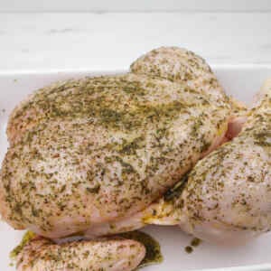 A seasoned whole roast chicken ready for the oven.
