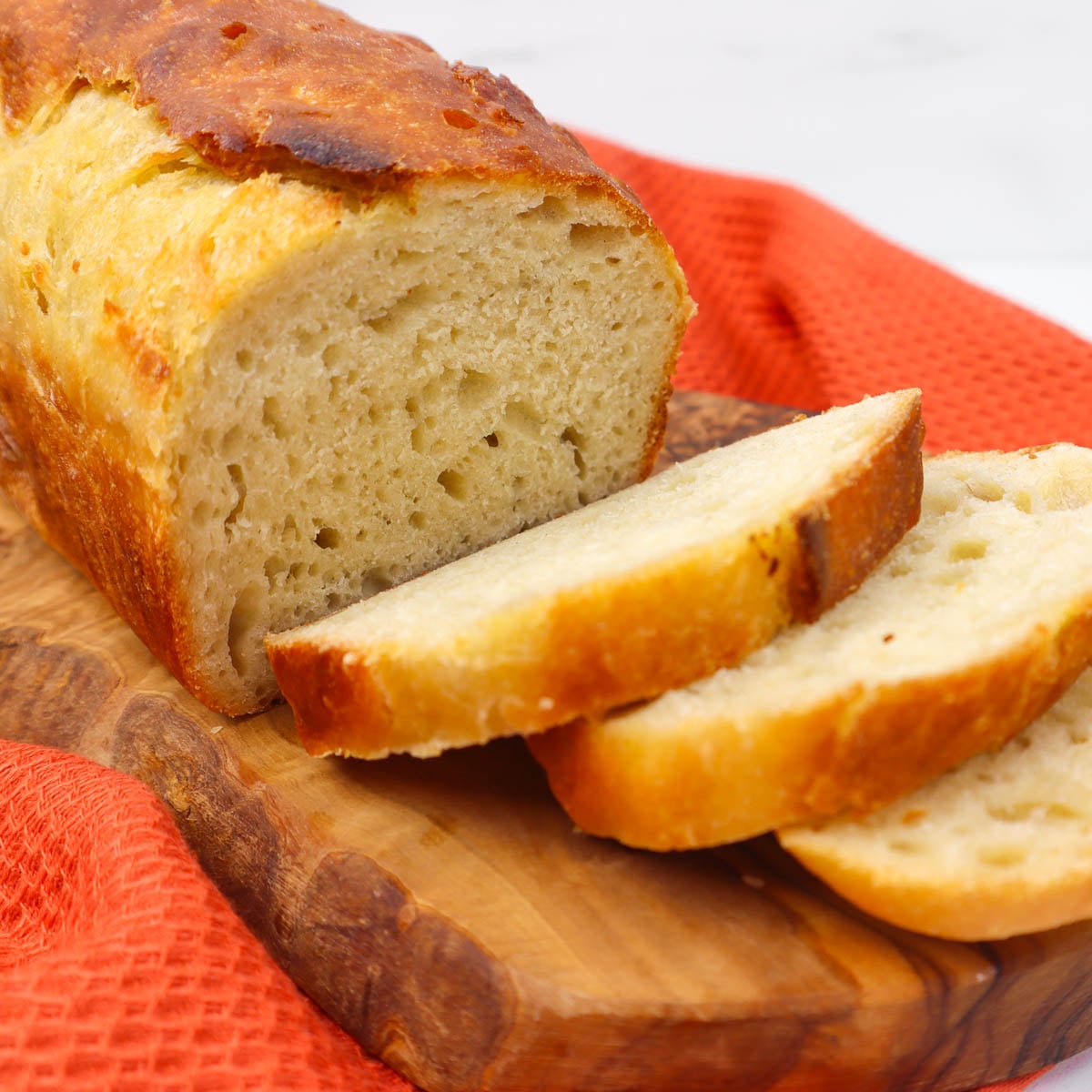 A sliced sourdough sandwich loaf on a wooden cutting board.