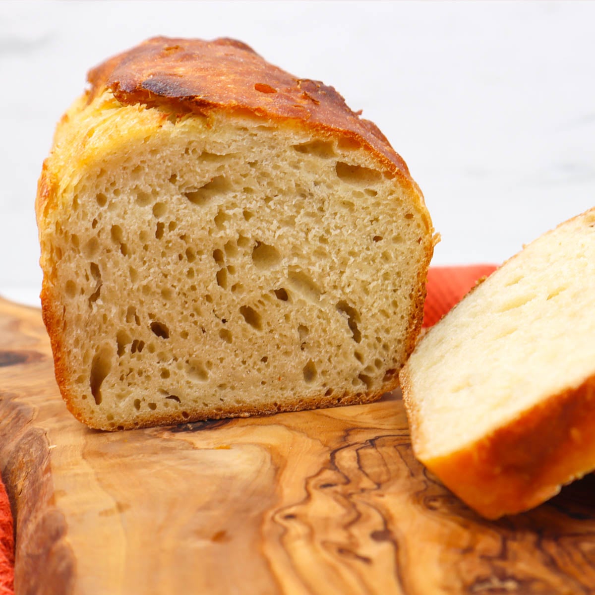 Sourdough Sandwich Loaf A sliced sourdough sandwich loaf showing its airy texture and golden crust on a wooden board.