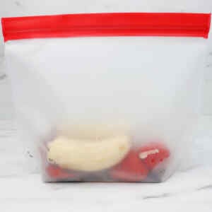 A freezer bag containing sliced bananas and strawberries for smoothie prep.
