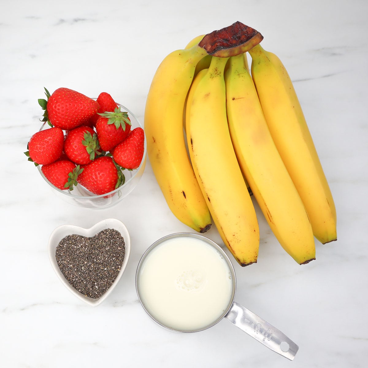 Strawberry and Banana Smoothie Freezer Meal Prep Packs Fresh strawberries and bananas with chia seeds and milk for smoothie prep.