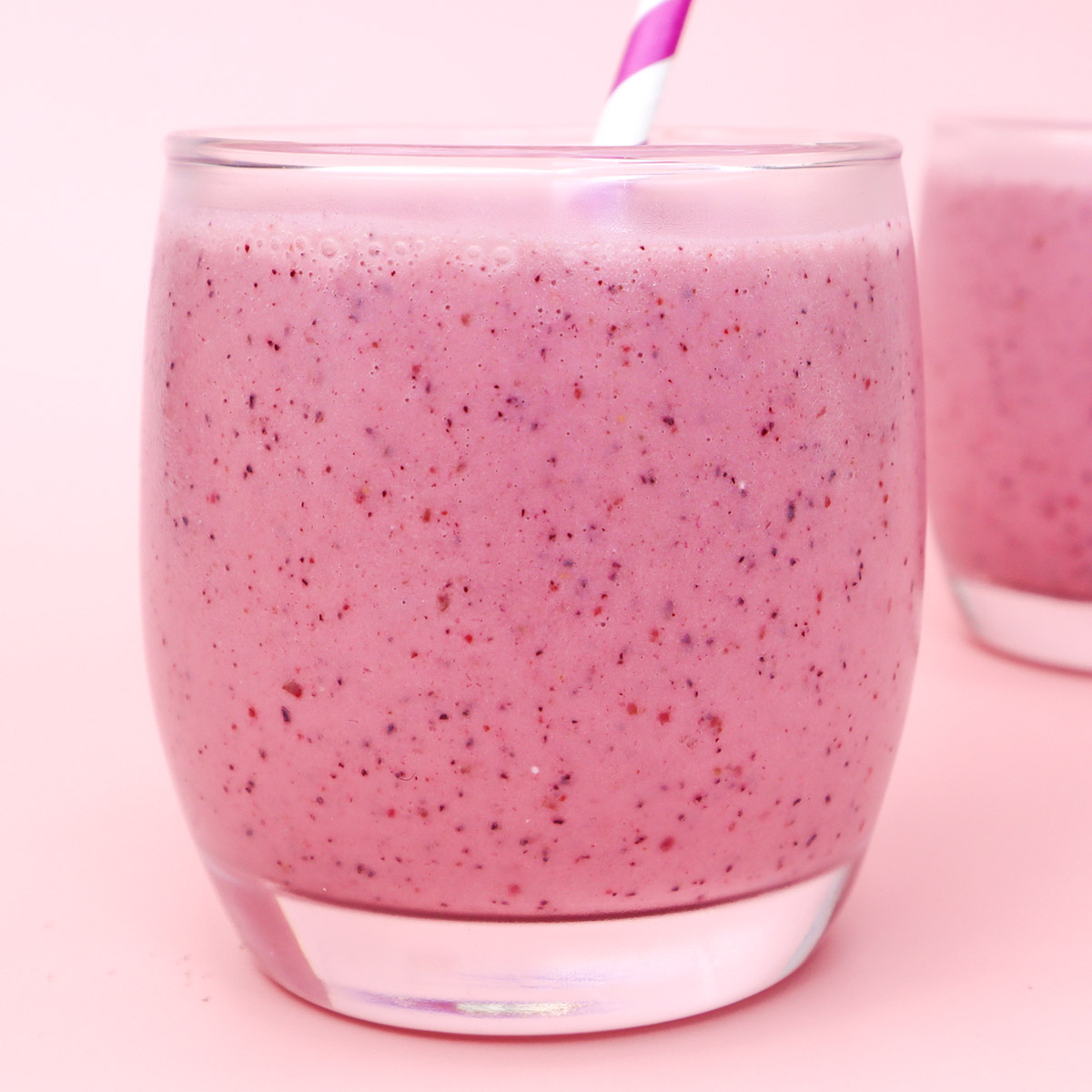 Paquetes de preparación de comidas congeladas con batidos de frutos rojos Primer plano de un batido de frutos rojos rosados en un vaso con pajita.