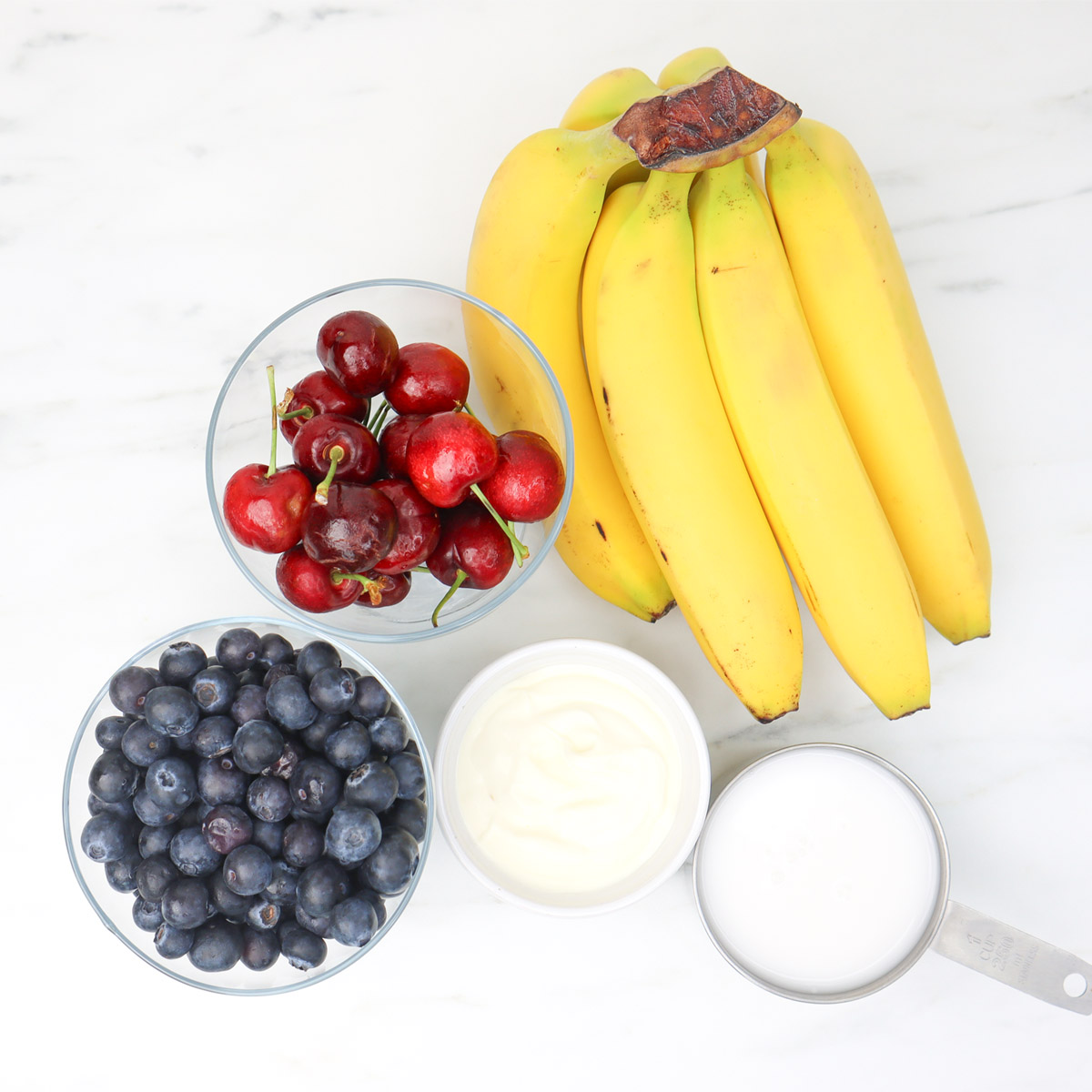 Paquetes de preparación de comidas congeladas con batidos de frutos rojos Ingredientes para un batido de frutos rojos, que incluye plátanos, cerezas, arándanos, yogur y leche.