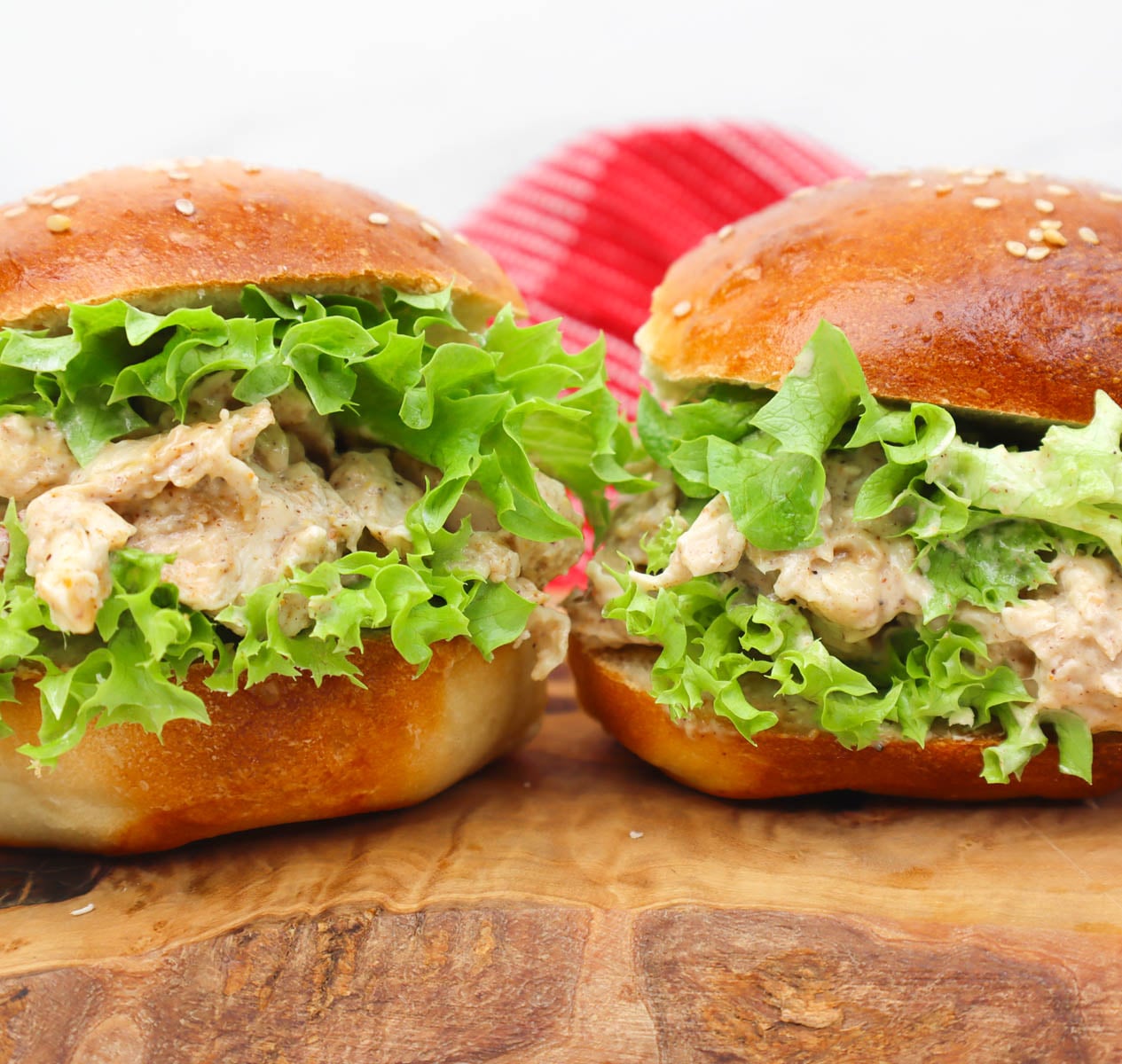 Coronation Chicken Sandwich Two coronation chicken sandwiches with lettuce on a wooden board.