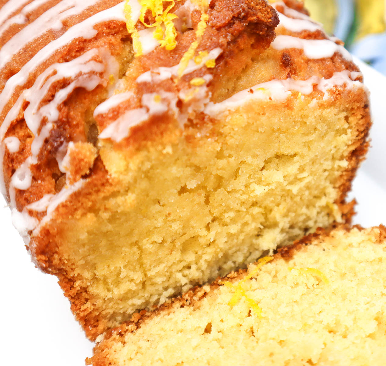 Lemon Drizzle Cake Close-up of a sliced lemon drizzle cake with a glossy icing and lemon zest on top.