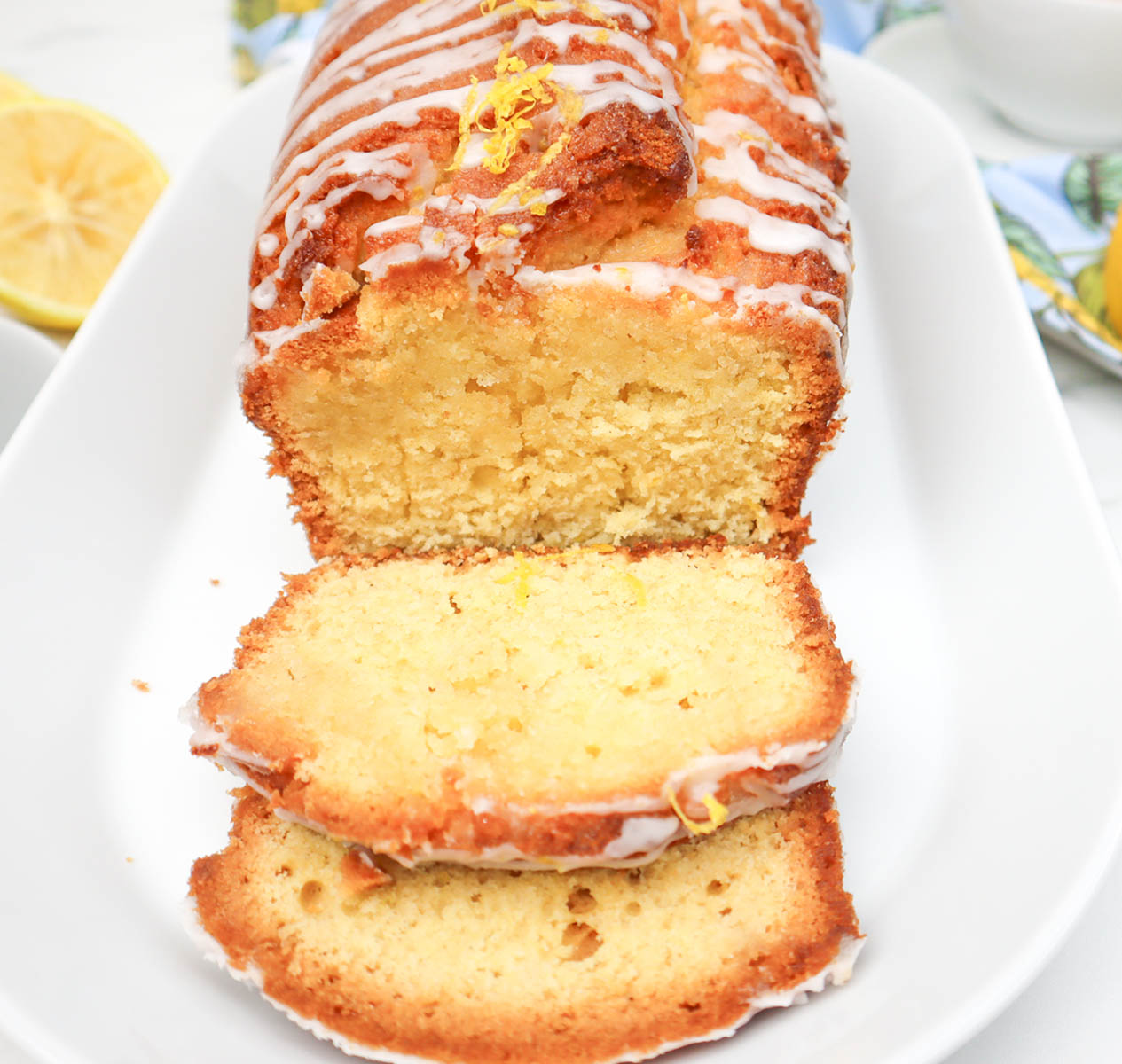 Lemon Drizzle Cake Sliced lemon drizzle cake with a glossy icing and lemon zest on top.