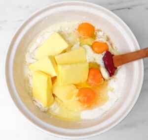 Ingredients for lemon drizzle cake, including butter, eggs, and flour, mixed in a bowl.