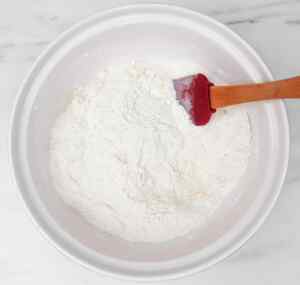 A bowl of flour and lemon zest with a spatula resting inside, ready for baking.