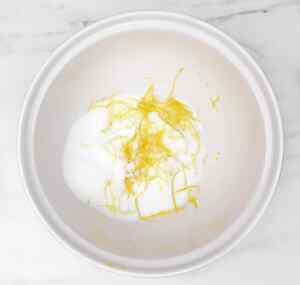 A mixing bowl with sugar and lemon zest for lemon drizzle cake preparation.