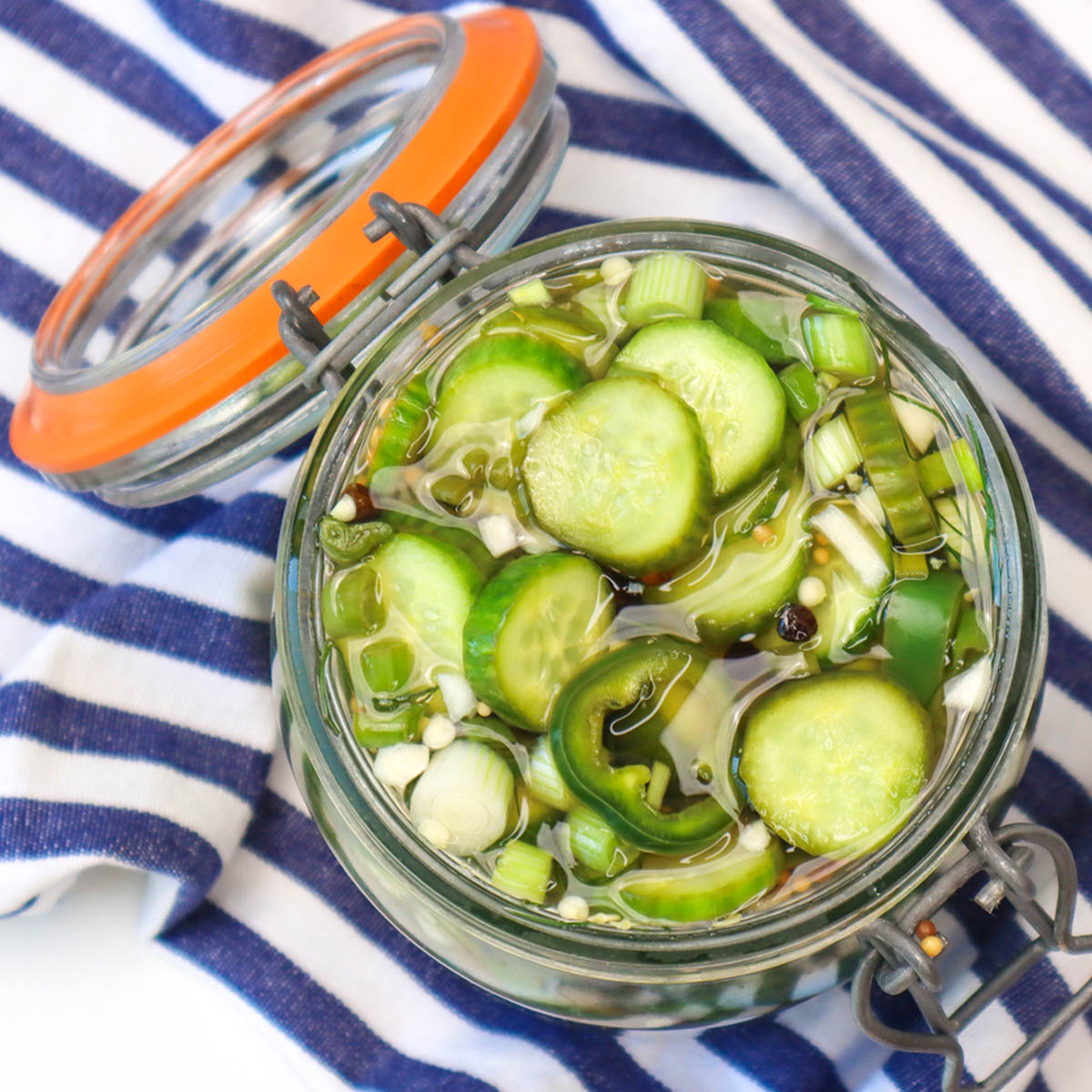 Quick Pickled Cucumbers A jar of quick pickled cucumbers with sliced cucumbers and green onions in a tangy brine.