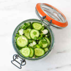 A jar filled with sliced cucumbers and green onions, ready for quick pickling.