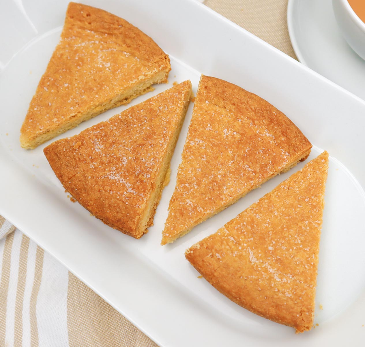 Scottish shortbread Three triangular pieces of golden Scottish shortbread on a white platter.