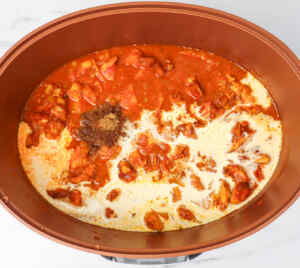 A slow cooker filled with chicken tikka curry, featuring a rich sauce and spices.