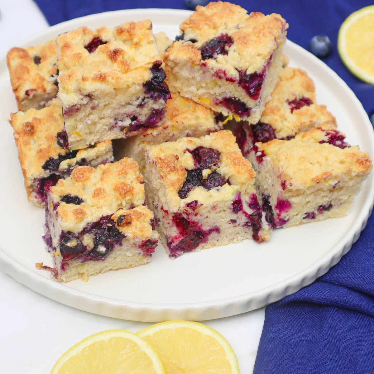 American Style Blueberry Biscuits A plate of American style blueberry biscuits, golden and fluffy, with fresh blueberries and lemon slices nearby.