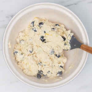 A bowl of blueberry biscuit dough with visible blueberries mixed in.