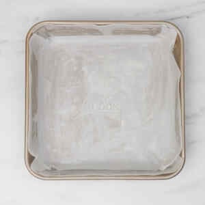 A baking pan lined with parchment paper, ready for blueberry biscuits.